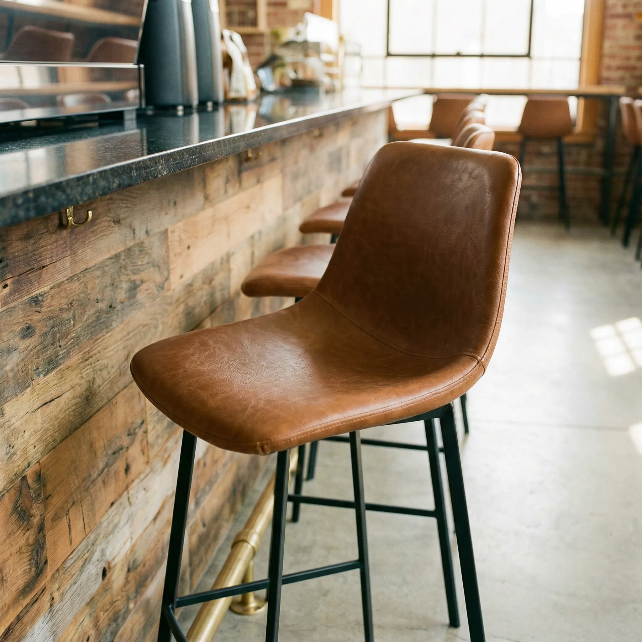 Kožne barske stolice sa metalnim okvirom uz šank od recikliranog drveta