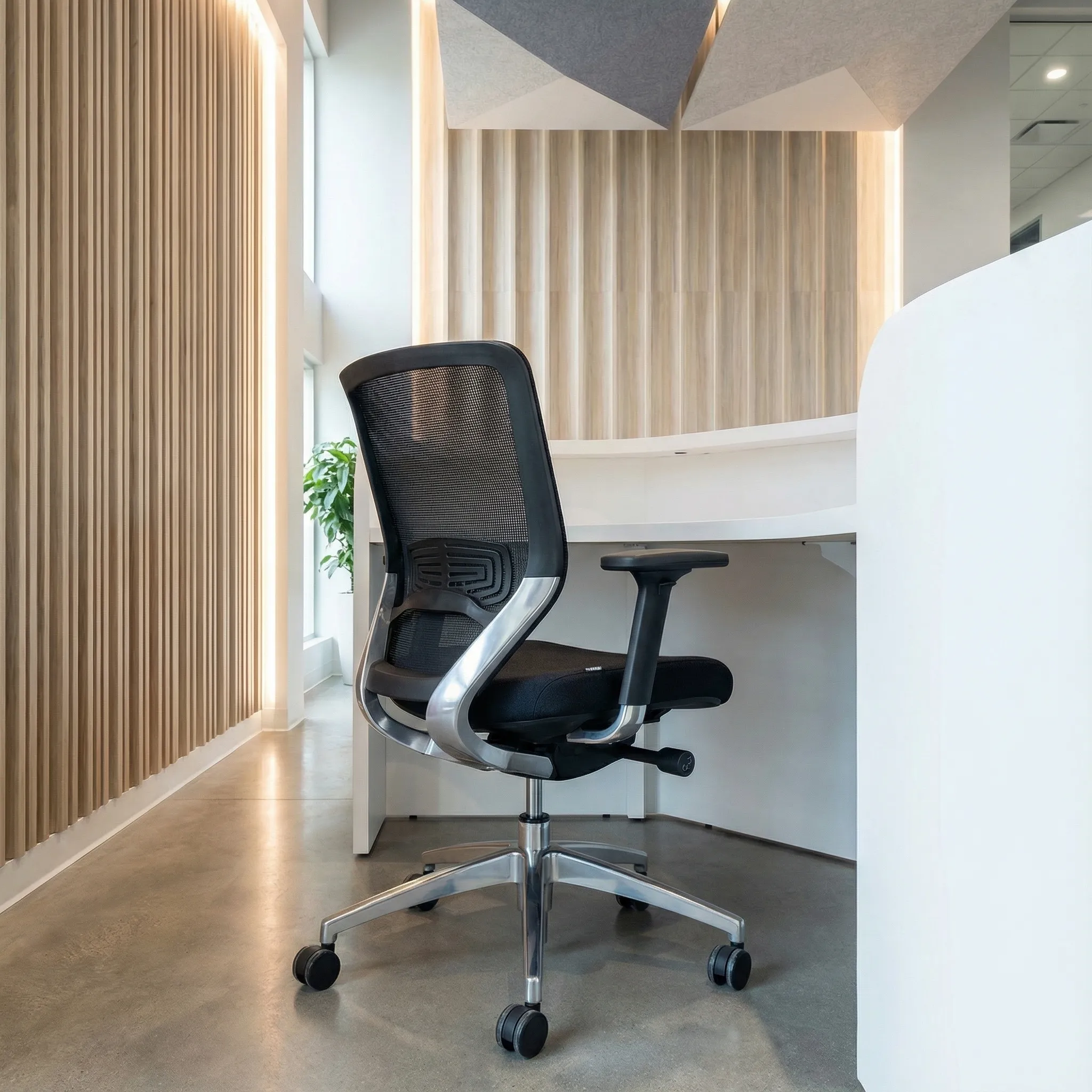 Ergonomska kancelarijska stolica iza recepcijskog pulta sa akustičnim panelima na plafonu